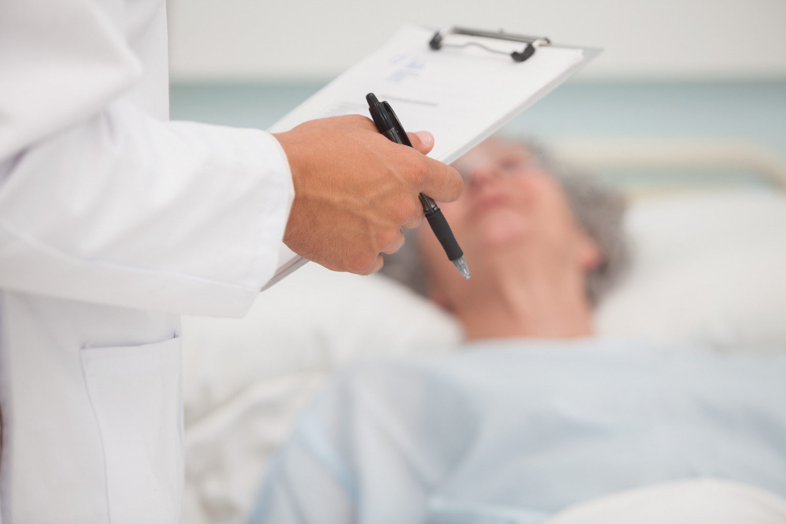 A doctor with a clipboard helping an elderly woman